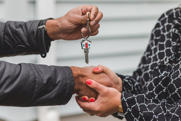 Florida Hometown Heroes. Close-up of a realtor handing over a house key to a new homeowner, symbolizing ownership and investment.