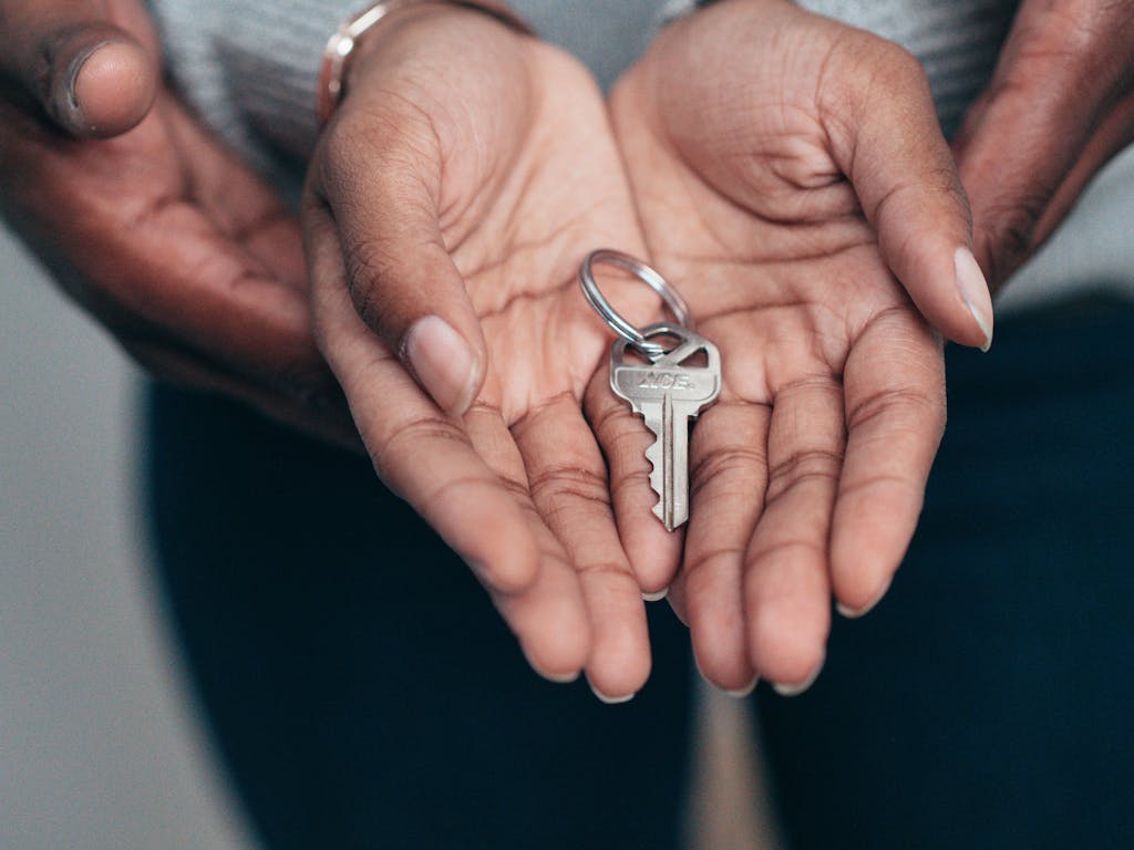 Florida Assist. Close-up of hands holding a key, symbolizing homeownership, real estate, and property investment.