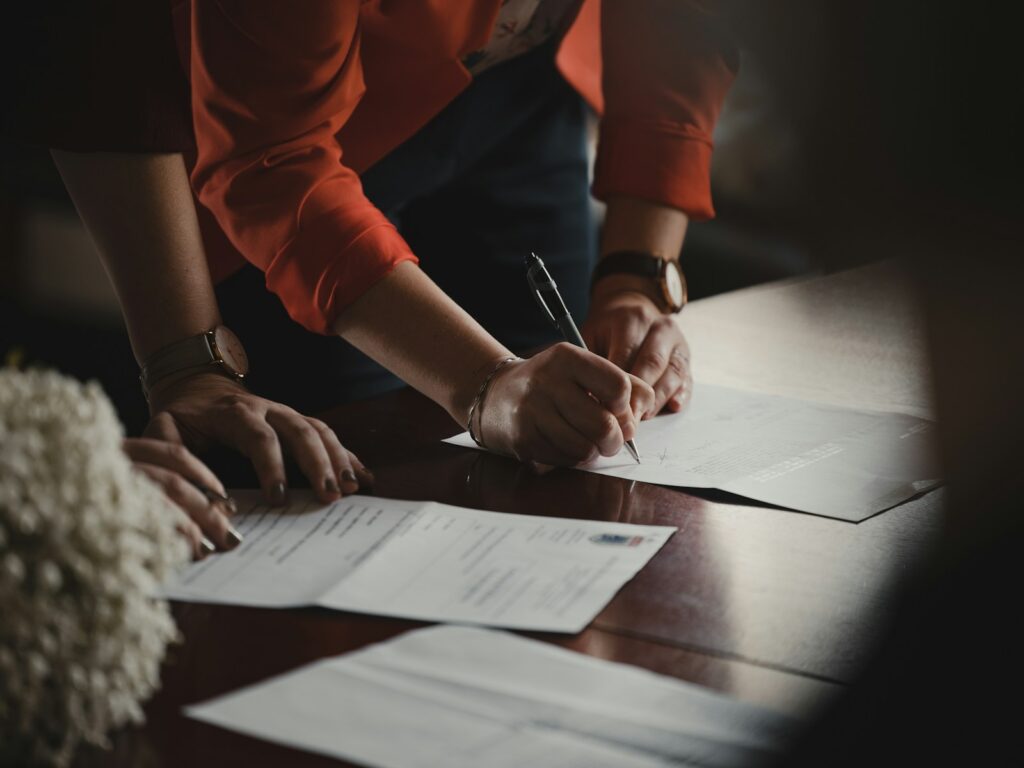 The 9-5 Real Estate Agent. A person in orange long sleeve shirt writing on white paper