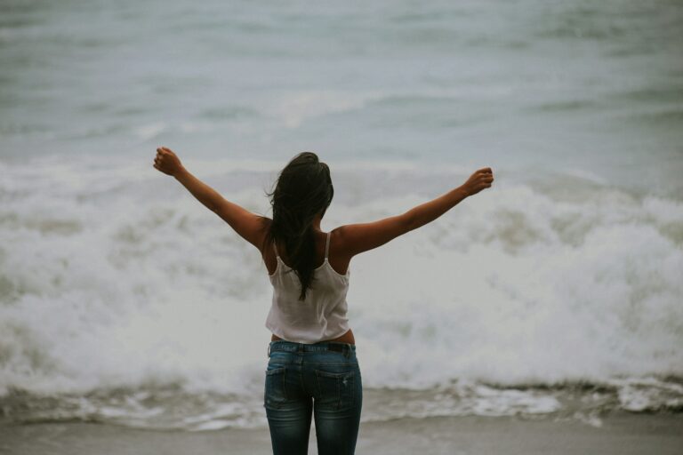 The 9-5 Real Estate Agent. Woman in white spaghetti strap top standing on the seashore