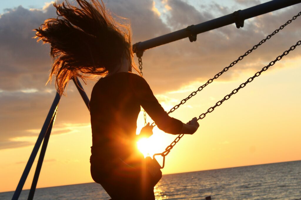 The 9-5 Real Estate Agent. A woman riding on swing during sunset