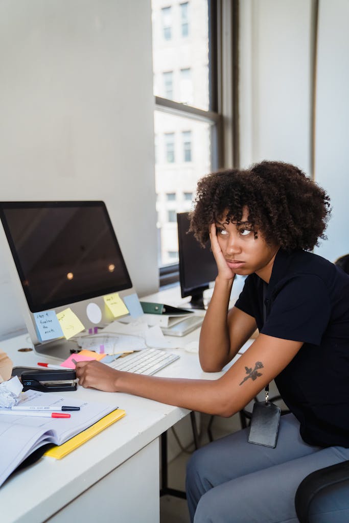 Woman looks frustrated at her office desk filled with notes as she contemplates the subscription to struggle.